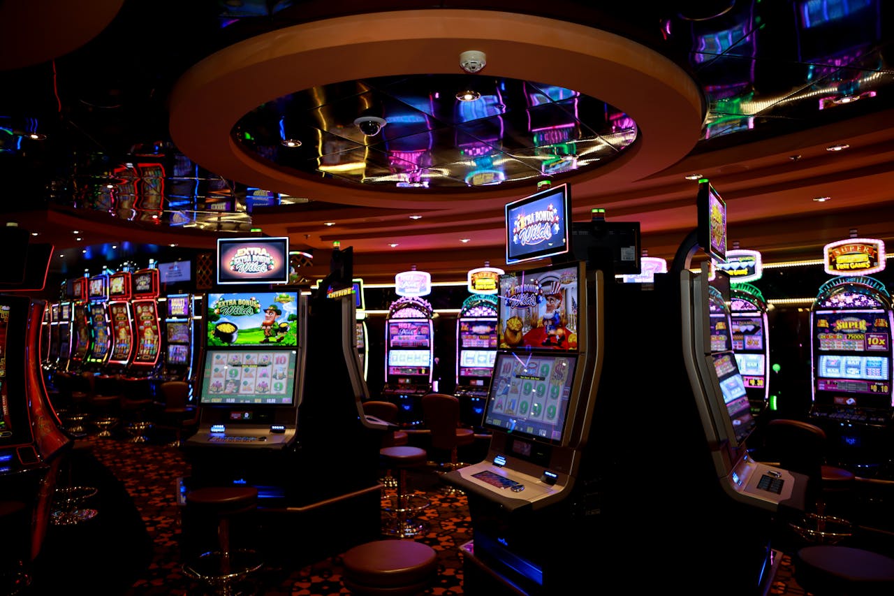 Contact Vibrant casino floor with colorful slot machines and bright lights capturing a lively gaming atmosphere.